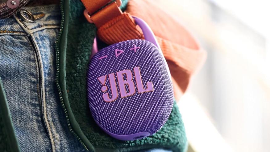 JBL Clip 5 Bluetooth speaker attached to a bag strap.