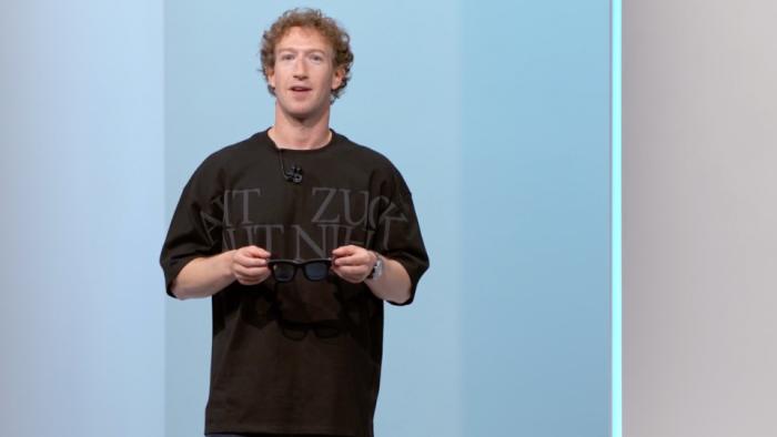 Mark Zuckerberg onstage, holding a pair of glasses, at Meta Connect 2024.