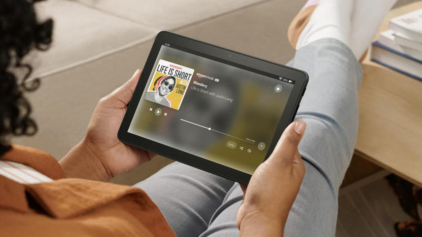 A person sitting comfortably, legs kicked up, reading the Fire HD 8 tablet.