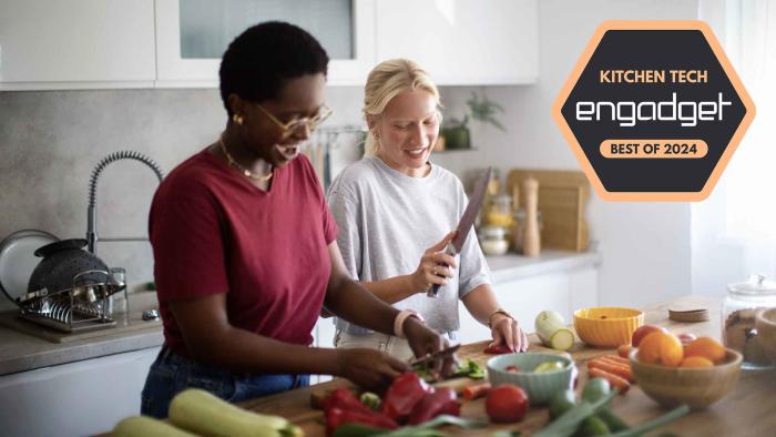 Two young women preparing meal in the kitchen. They are having fun and cutting the vegetables together.