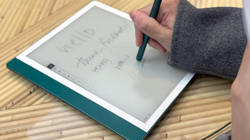 The Amazon Kindle Scribe held in mid-air, with a skylight and buildings in the background.